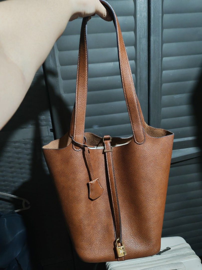 Imported Brown Leather Bucket Tote Bag with Lock (Category: Tote Bags) located in Caloocan City. Submitted by mommyella22 (Listing ID 1448621677, Image 1). Description: - Classic brown leather bucket bag - Pebbled leather texture - Includes small padlock and key - Comfortable top handles Super Gandaaa - Simple and chic design - Ideal for everyday wear BKK bought🇹🇭.