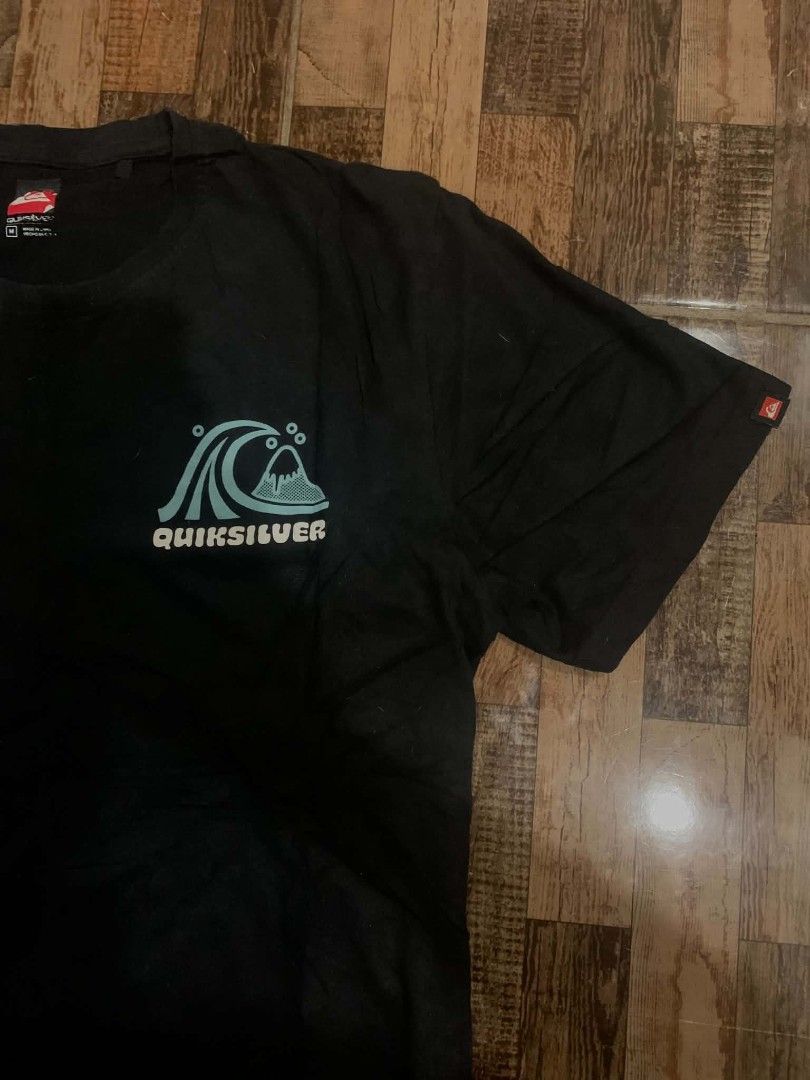 Quiksilver Black T-shirt with Wave Logo (Category: Tshirts & Polo Shirts ) located in Manila. Submitted by gerardthrifted (Listing ID 1448645409, Image 2). Description: - Brand: Quiksilver - Color: Black - Size: Medium (M) - Design: Features the Quiksilver wave logo on the front left chest and a larger wave graphic on the back. - Material: 100% Cotton - Style: Ideal for casual wear.