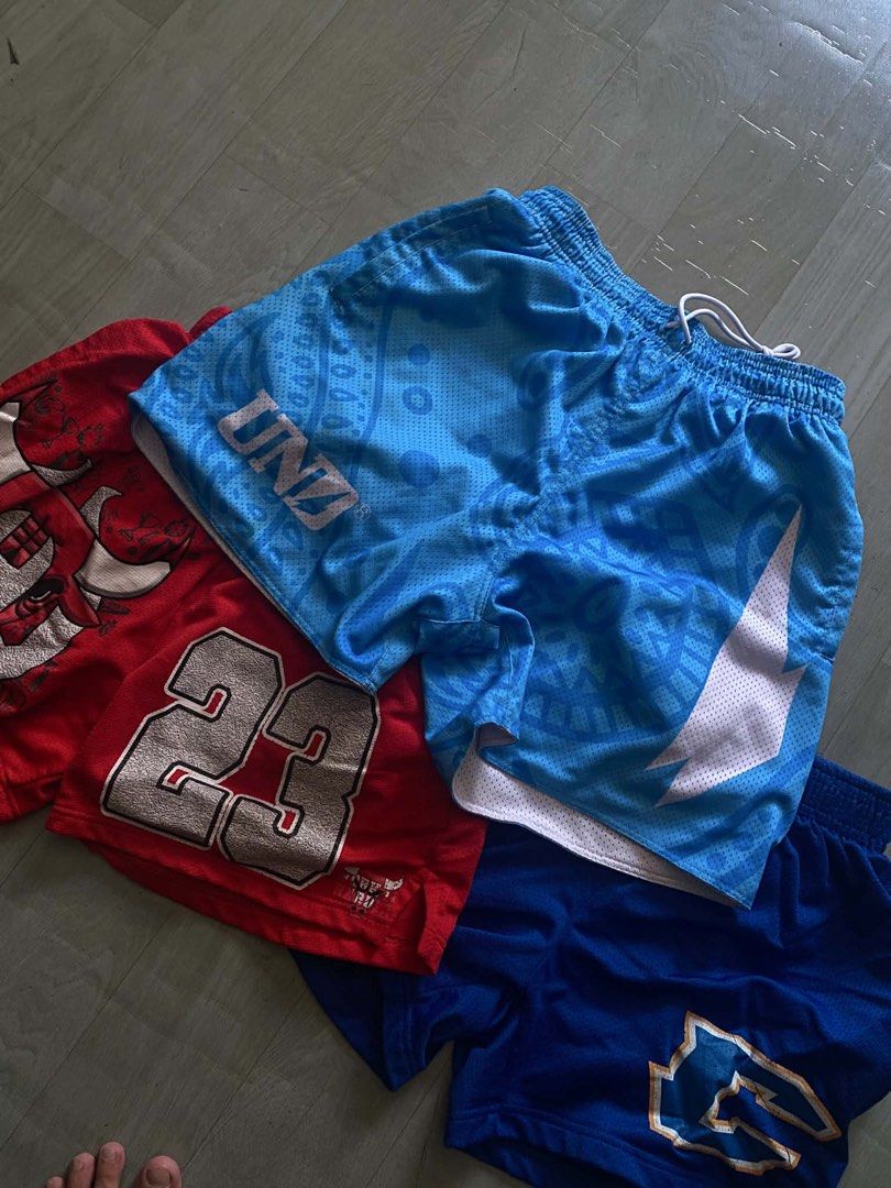 RUSH BUNDLE (Category: Shorts) located in Pasig City. Submitted by khiarha (Listing ID 1448568882, Image 1). Description: - Bundle of 3 athletic shorts - Includes: 1 red pair ('23' graphic), 1 light blue pair ('UNZ' & Nike-like swoosh), 1 solid blue pair - Ideal for sports and casual wear - Features elastic waistbands with drawstrings.