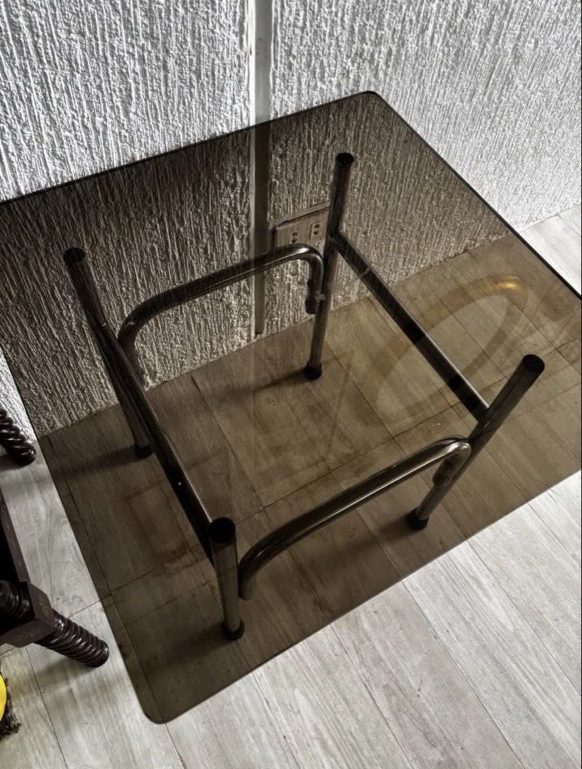Square Glass Top Side Table with Metal Frame (Category: Tables & Sets) located in Las Pinas. Submitted by timelessthread (Listing ID 1448694576, Image 3). Description: - Compact square side table - Smoked glass top - Sturdy metal frame - Protective leg caps - Ideal for small spaces or as an accent piece - May small chip sa gilid 2 yun pero di masyado halata kasi dark sya - 55 cm ang taas - 24”x24” yung dimension nung glass.