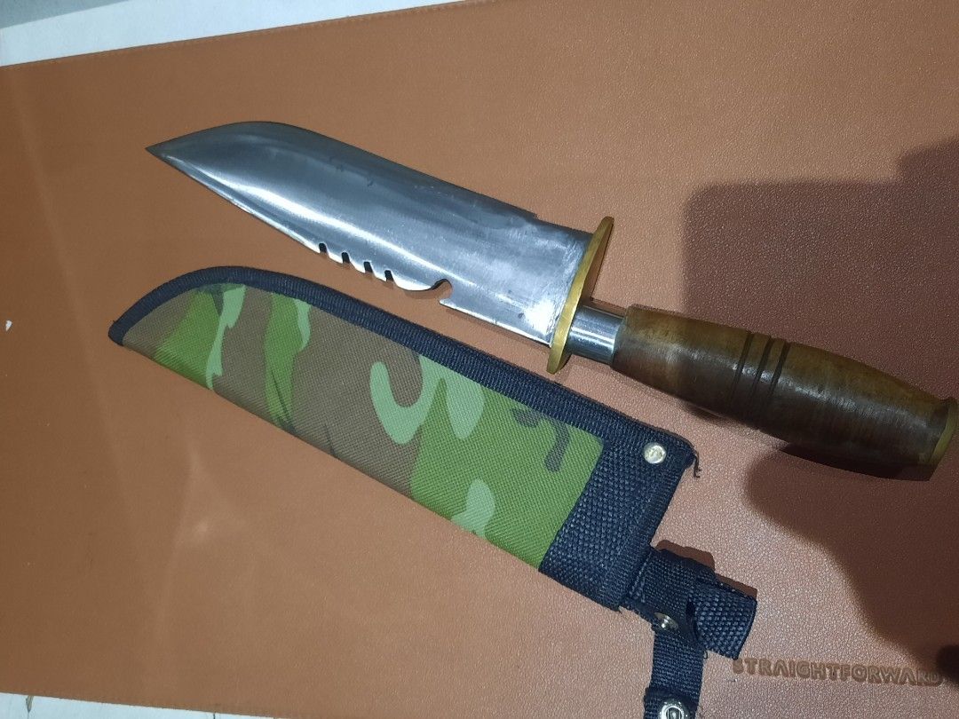 Survival Knife with Sheath (Category: Hiking & Camping) located in Manila. Submitted by epictree.a37e8d (Listing ID 1448632488, Image 1). Description: - Heavy duty survival knife set - Includes two knives - Durable camouflage sheath for one knife - Second black sheath with decorative carvings - One knife features a wooden handle - Second knife has a dark grey handle - Ideal for camping and outdoor activities.