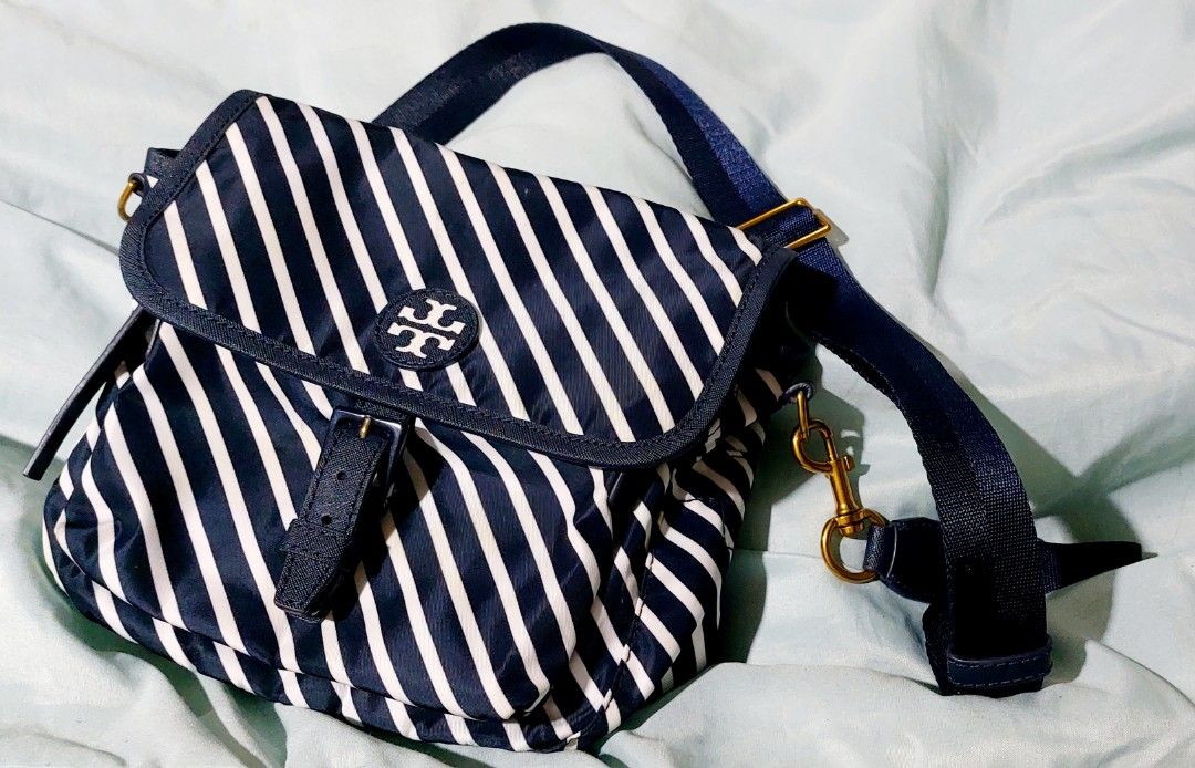 Tory Burch Striped Nylon Crossbody Bag (Category: Luxury Bags & Wallets) located in Cainta. Submitted by veronica2277 (Listing ID 1448531947, Image 1). Description: Almost new original navy white striped Tory Burch shoulder/body bag. Very nice and light. - Durable nylon material with leather trim - Main compartment with interior zip pocket - Front flap closure with secure snap button - Adjustable strap for comfortable wear - Elegant gold hardware
