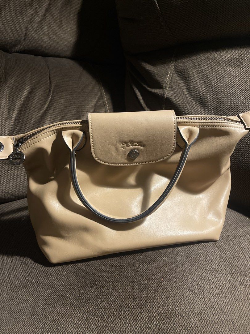 Longchamp Le Pliage Cuir Leather Handbag (Category: Luxury Bags & Wallets) located in Ozamiz City. Submitted by mick_cab (Listing ID 1453175409, Image 1). Description: - Authentic Longchamp handbag in a versatile light beige color. - Crafted from soft, genuine leather for a luxurious feel. - Secure zip closure with an additional snap button flap for added security. - Contrasting darker grey handles add a stylish detail. - Exceptionally spacious i