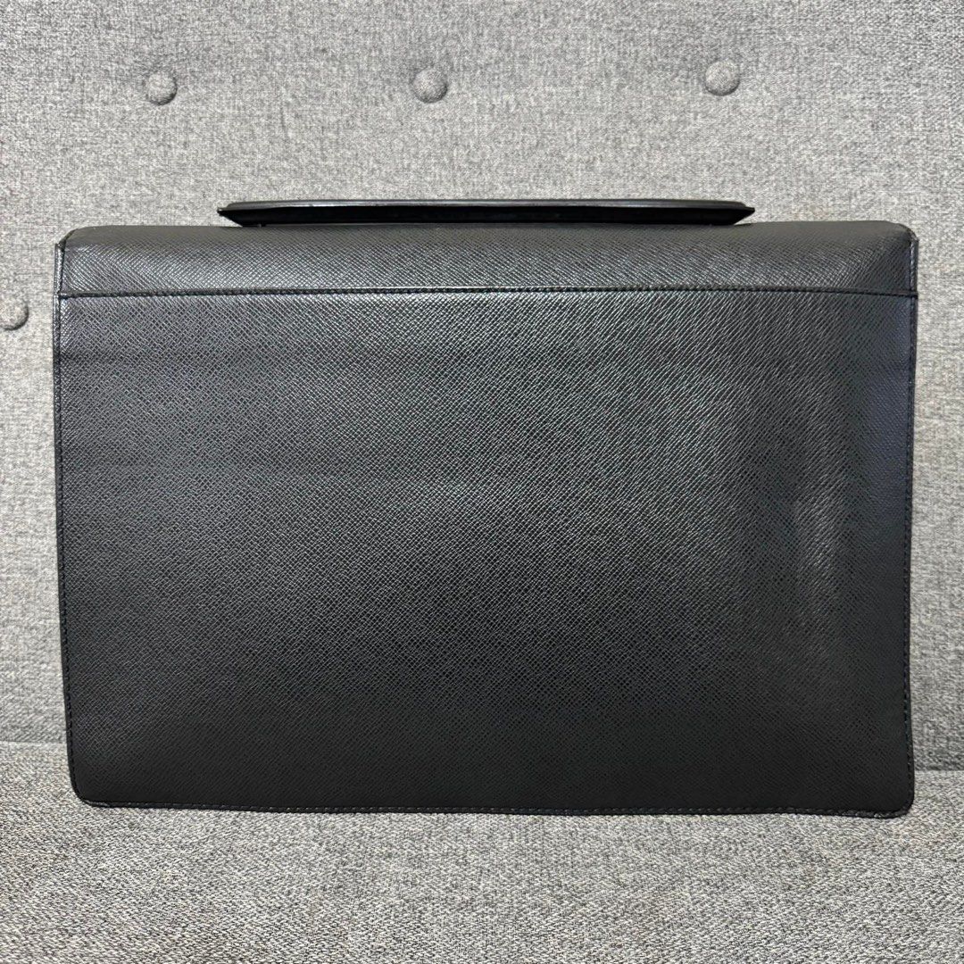 Louis Vuitton Taiga Leather Briefcase (Category: Luxury Bags & Wallets) located in Madrid. Submitted by jhunaceee (Listing ID 1453180962, Image 2). Description: - Classic Black Taiga leather briefcase - Silver-tone clasp closure - Ample interior space for documents and laptop - Top handle for carrying - Clean interior - Shows some signs of wear on exterior leather and hardware - Solid, professional bag.