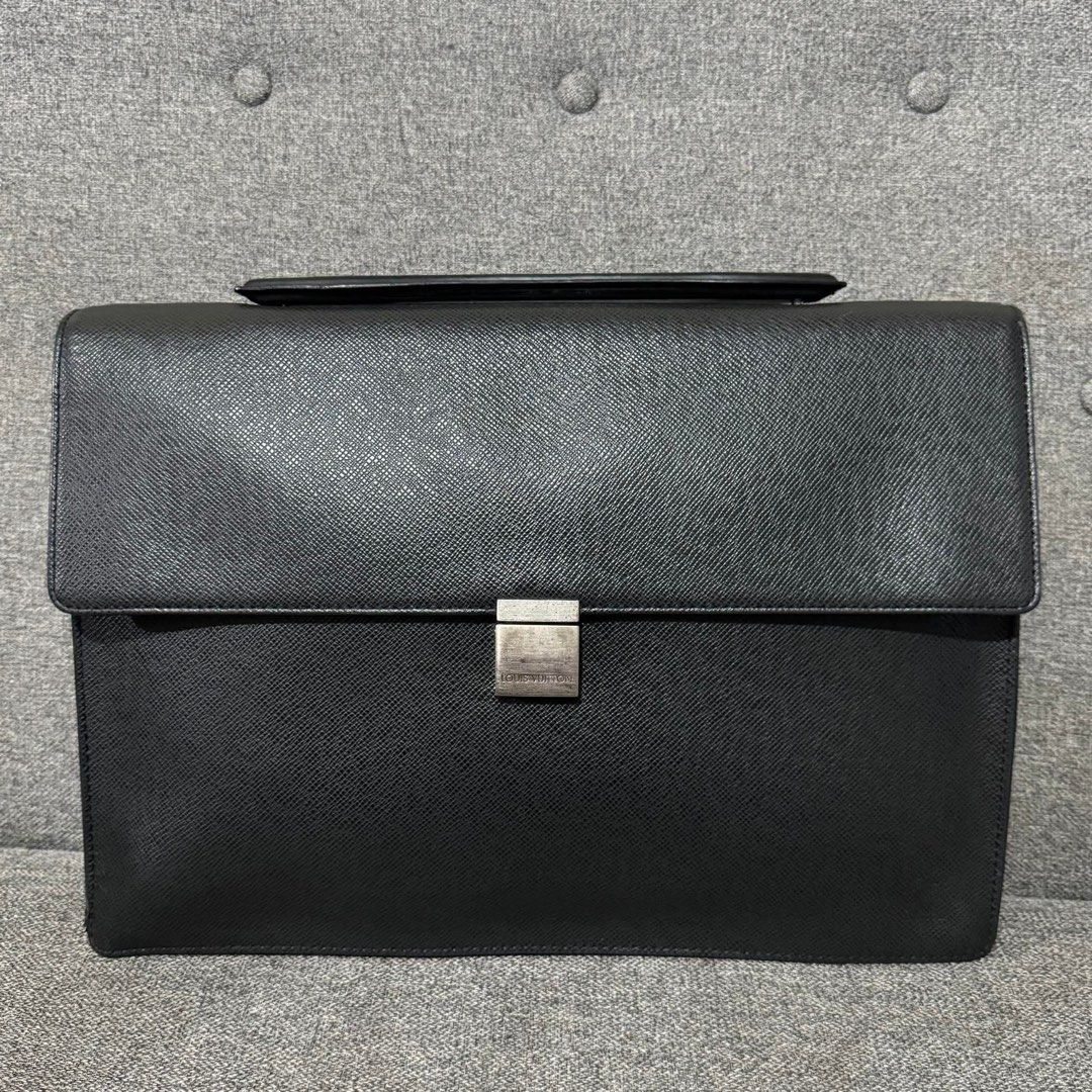 Louis Vuitton Taiga Leather Briefcase (Category: Luxury Bags & Wallets) located in Madrid. Submitted by jhunaceee (Listing ID 1453180962, Image 1). Description: - Classic Black Taiga leather briefcase - Silver-tone clasp closure - Ample interior space for documents and laptop - Top handle for carrying - Clean interior - Shows some signs of wear on exterior leather and hardware - Solid, professional bag.