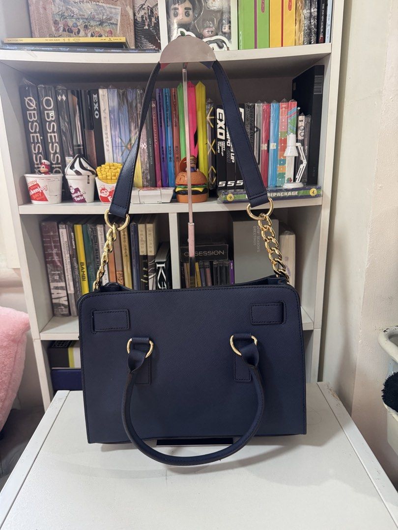 Michael Kors MK Navy Hamilton Medium Satchel Bag (Category: Luxury Bags & Wallets) located in Manila. Submitted by antonettegan (Listing ID 1453057409, Image 2). Description: - Navy blue Michael Kors handbag - Elegant gold hardware details - Removable chain strap for versatile styling - Interior features a zip pocket and a slip pocket - Ample space for all your essentials - Perfect for everyday wear or dressing up for special occasions.