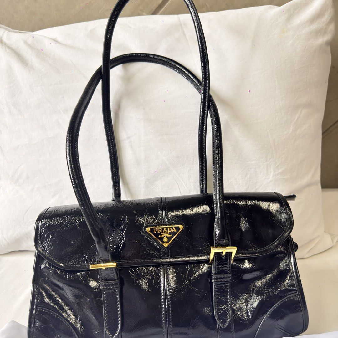 Prada Black Patent Leather Shoulder Bag (Category: Luxury Bags & Wallets) located in Mabalacat. Submitted by kay_miscak (Listing ID 1453114951, Image 1). Description: -Prada black patent leather shoulder bag - Elegant gold hardware details - Comfortable top handles - Secure buckle closures on the front - Lampo under zip -with black and white Prada tag - Spotless and clean interior - A truly classic and versatile piece for any wardrobe.