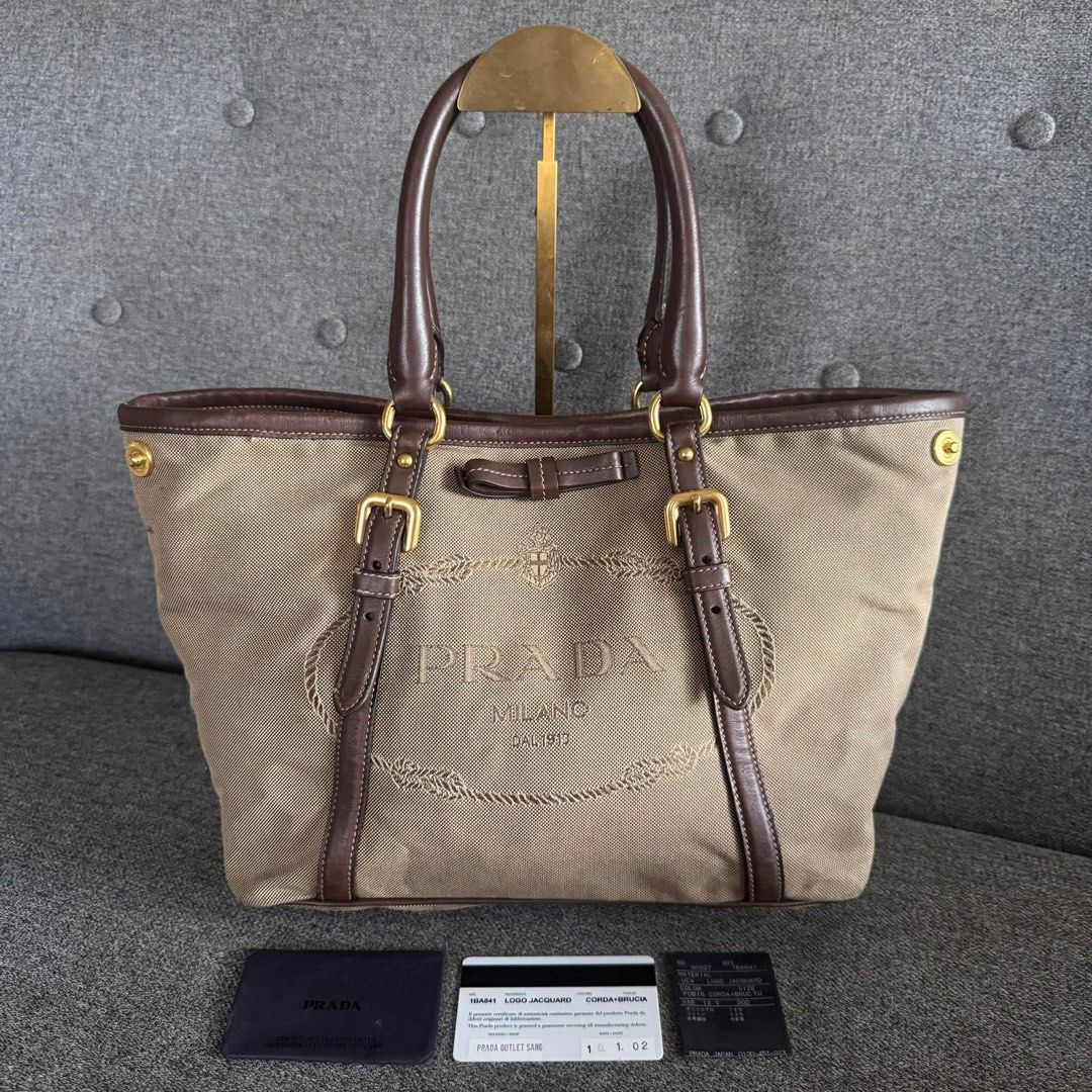 Prada Milano Canvas Leather Trim Tote Bag (Category: Luxury Bags & Wallets) located in Madrid. Submitted by jhunaceee (Listing ID 1453180428, Image 1). Description: - Authentic Prada tote bag - Color: Beige canvas with dark brown leather trim and handles - Hardware: Gold - Features: Embossed Prada Milano logo on front - Interior: Spacious, ideal for essentials - Perfect for: Everyday use.