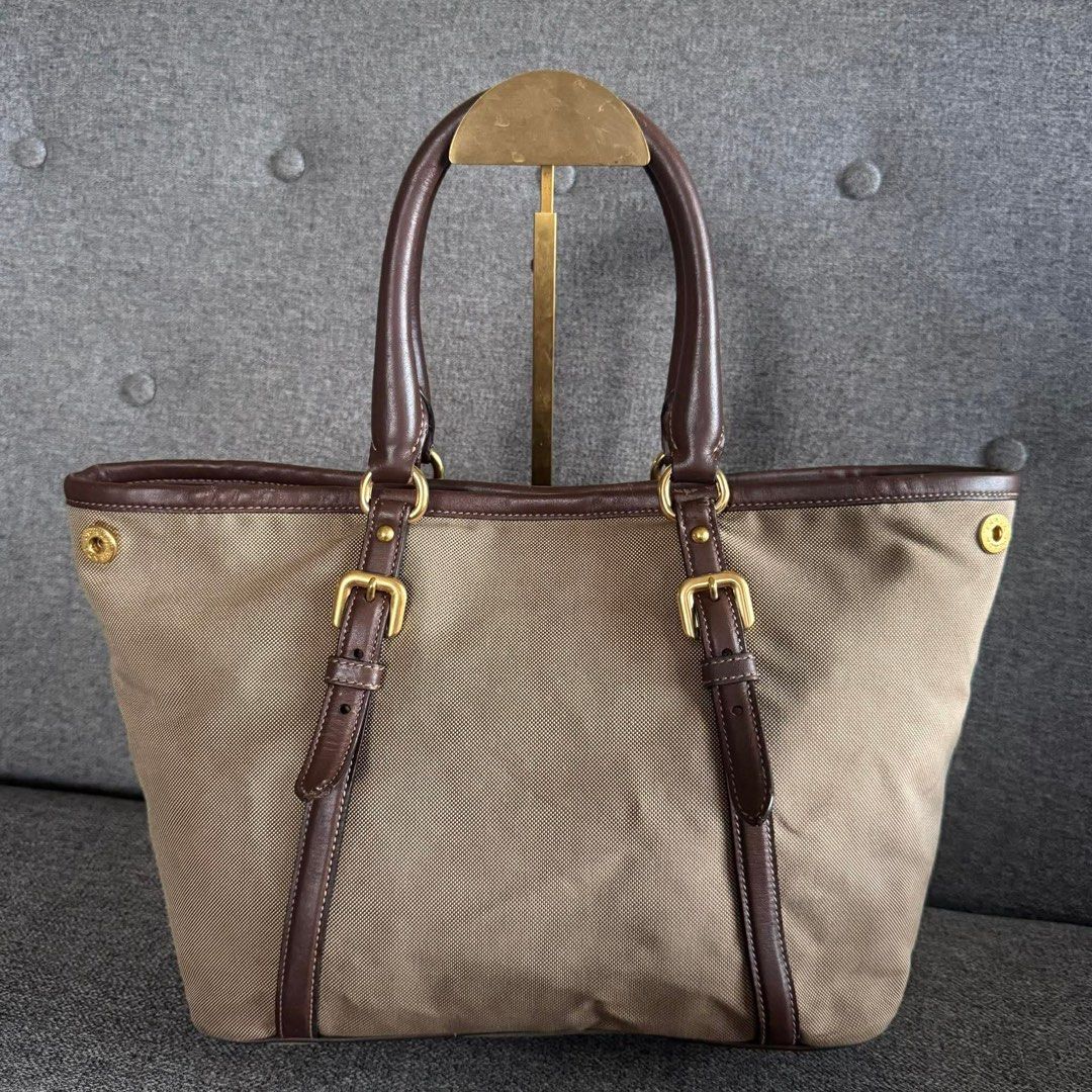 Prada Milano Canvas Leather Trim Tote Bag (Category: Luxury Bags & Wallets) located in Madrid. Submitted by jhunaceee (Listing ID 1453180428, Image 2). Description: - Authentic Prada tote bag - Color: Beige canvas with dark brown leather trim and handles - Hardware: Gold - Features: Embossed Prada Milano logo on front - Interior: Spacious, ideal for essentials - Perfect for: Everyday use.