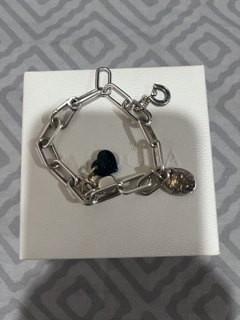 RuSH: Authentic Pandora Sterling Silver Bracelet with Charms (Category: Bracelets) located in Taguig. Submitted by silverrabbit.e27e96 (Listing ID 1453234184, Image 1). Description: - Sterling silver paperclip chain bracelet - Features a unique horseshoe clasp - Includes a dark green heart charm - Comes with a small oval charm showcasing a rose - Ideal for layering with other bracelets or as a standalone piece - Resembles a Pandora bracelet style
