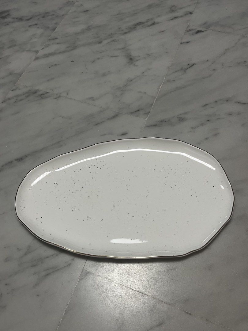Serving Platter (Category: Dinnerware & Cutlery) located in Singapore. Submitted by design.shopping (Listing ID 1453053797, Image 1). Description: - White speckled serving platter (36cm) - Unique irregular shape - Thin gold rim detail - Brand new - Ideal for appetizers, snacks, or small dishes - Adds a unique touch to any table setting - Suitable for parties and everyday use.