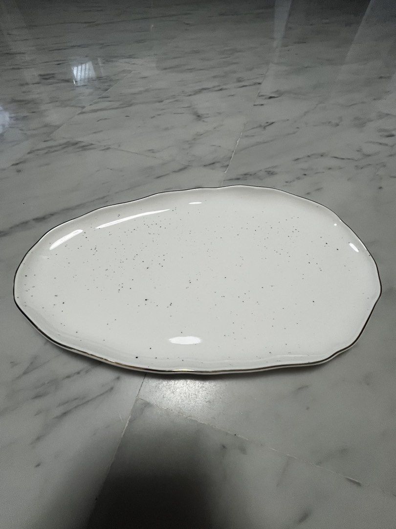 Serving Platter (Category: Dinnerware & Cutlery) located in Singapore. Submitted by design.shopping (Listing ID 1453053797, Image 3). Description: - White speckled serving platter (36cm) - Unique irregular shape - Thin gold rim detail - Brand new - Ideal for appetizers, snacks, or small dishes - Adds a unique touch to any table setting - Suitable for parties and everyday use.