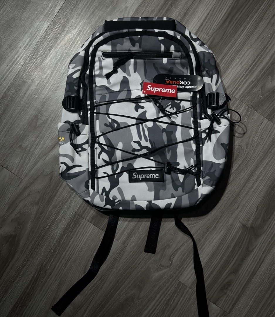 Supreme Camo Backpack CORDURA Fabric (Category: Backpacks) located in Manila. Submitted by pm302957949932 (Listing ID 1453178381, Image 1). Description: - Supreme backpack in stylish grey camo pattern. - Constructed with highly durable CORDURA fabric for long-lasting use. - Equipped with adjustable straps for a comfortable fit. - Includes convenient bungee cord detailing on the front for extra storage or style. - Offers ample space to carry all y