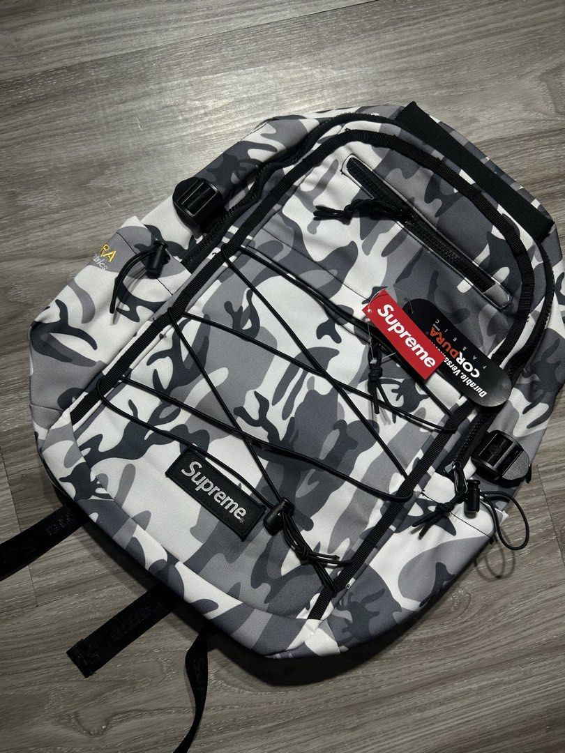 Supreme Camo Backpack CORDURA Fabric (Category: Backpacks) located in Manila. Submitted by pm302957949932 (Listing ID 1453178381, Image 2). Description: - Supreme backpack in stylish grey camo pattern. - Constructed with highly durable CORDURA fabric for long-lasting use. - Equipped with adjustable straps for a comfortable fit. - Includes convenient bungee cord detailing on the front for extra storage or style. - Offers ample space to carry all y