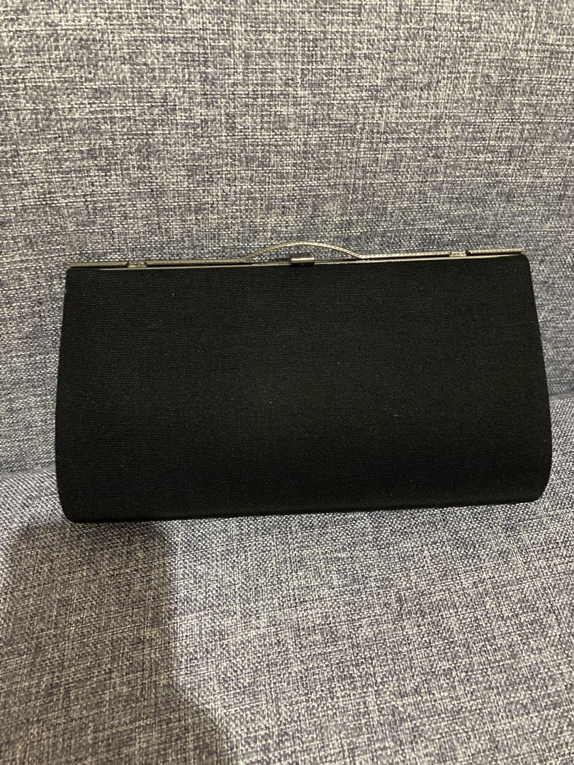 Black Fabric Clutch Bag with Silver Clasp (Category: Clutches) located in Valenzuela. Submitted by theaveqc04360 (Listing ID 1454905055, Image 1). Description: - Classic black clutch bag - Textured weave fabric exterior - Secure silver metal clasp closure - Interior includes a small chain strap - Built-in card slots for essentials - Perfect for evenings out or special occasions - Approximate dimensions: 9 inches wide, 4 inches tall.