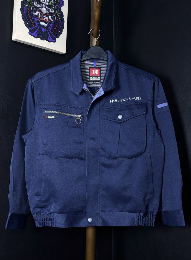 BURTLE WORKWEAR Navy Blue Jacket Size M (Category: Coats, Jackets and Outerwear) located in Bacoor. Submitted by calvinmanzano13 (Listing ID 1454785801, Image 1). Description: - L = 23.5” | W = 21.5” - Zip-up front closure - Multiple pockets, including a zippered chest pocket - Features Japanese text embroidery on front and sleeve - Elasticated cuffs and hem for a snug fit - Versatile for work or casual outfits Notes: ☑️ Brand new (removed tags b