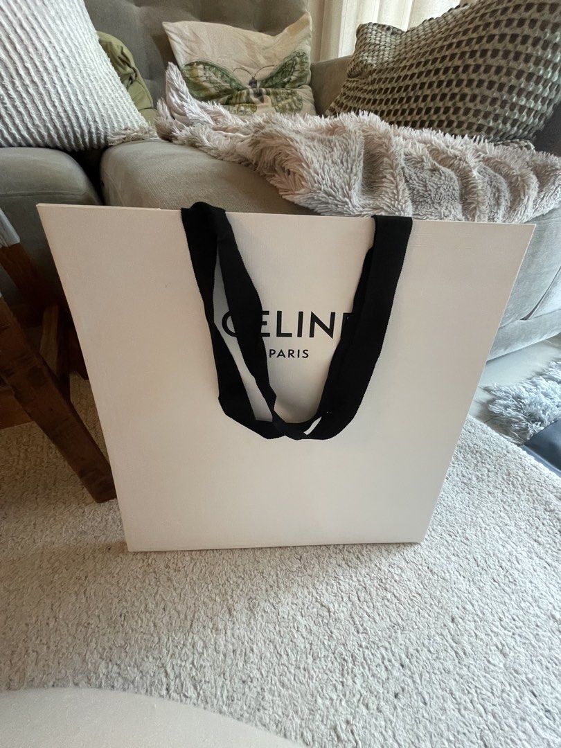 Celine Paper Bag Large (Category: Luxury Bags & Wallets) located in Pasig City. Submitted by tintin._. (Listing ID 1454852310, Image 1). Description: - Authentic Celine Paris shopping bag - Classic white with black handles - Ideal size for purchases or storage - Can be used as a stylish gift bag - Condition: Clean and sturdy.