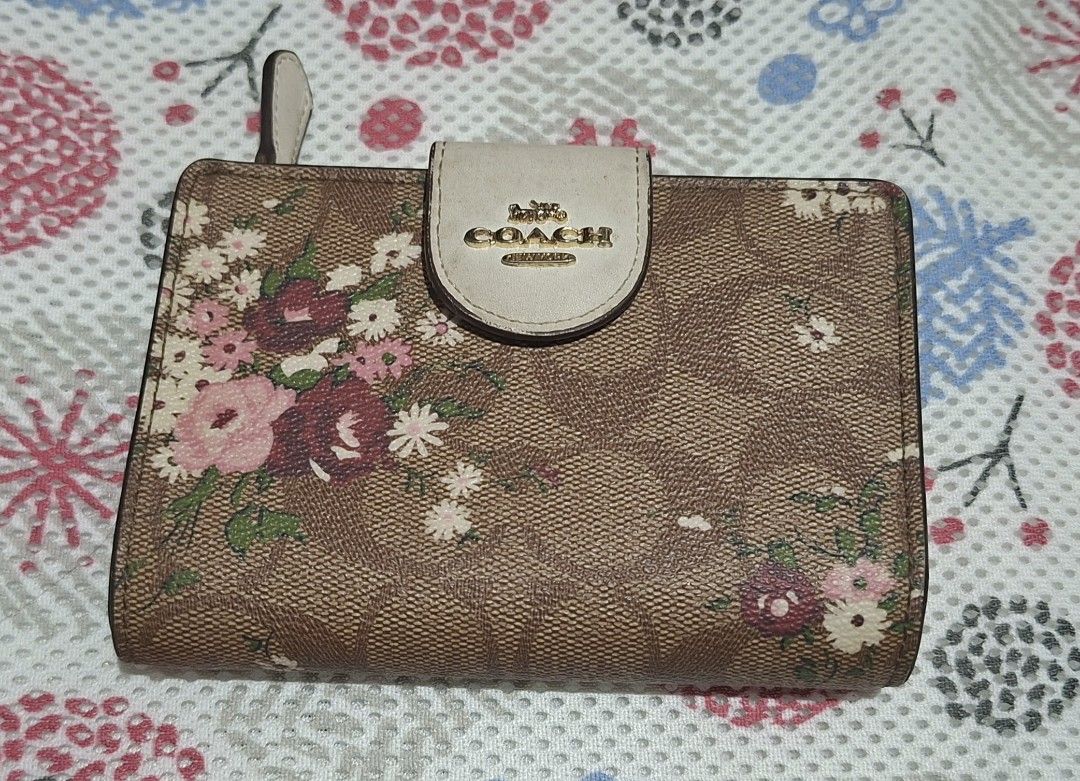 Coach Floral Print Bifold Wallet (Category: Wallets & Card holders) located in Muntinlupa City. Submitted by abunching (Listing ID 1454928844, Image 1). Description: - Coach bifold wallet (not original) - Adorable floral print design - Classic brown signature canvas exterior - Pretty pink interior - Multiple card slots for organization - Convenient zip coin pocket - Secure snap closure - Perfect for everyday essentials - Shows minor signs of wear