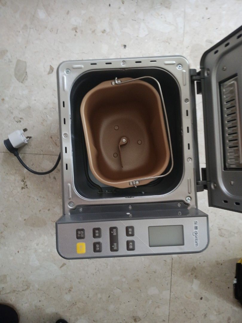 Donlim Bread Maker Machine (Category: Breadmakers) located in Singapore. Submitted by chessboy_carou (Listing ID 1454790394, Image 3). Description: - Donlim Bread Maker - Multiple settings for different bread types and dough - Comes with bread pan and kneading blade - Easy-to-use control panel with digital display - Perfect for fresh homemade bread - Plug visible in photo.