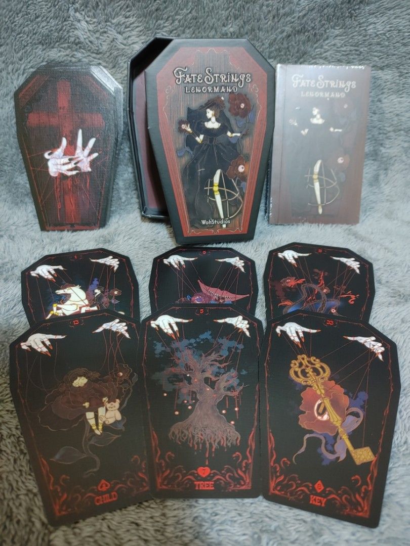 Fate Strings Lenormand (Category: Storybooks) located in Caloocan City. Submitted by adrienne_garcia (Listing ID 1454808250, Image 1). Description: Selling the Fate Strings Lenormand tarot deck. Comes in a unique coffin-shaped box. The cards have a dark, gothic aesthetic with intricate designs. Includes the main deck and a guidebook..