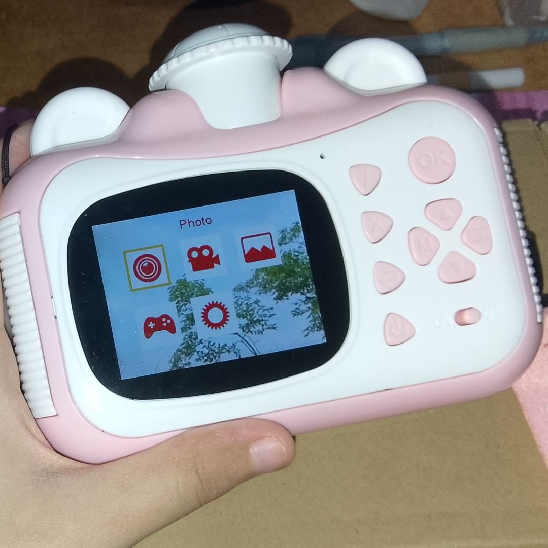 FXNFXLA Kids Instant Print Camera (Category: Cameras) located in Caloocan City. Submitted by acnl_ (Listing ID 1454933073, Image 3). Description: A 2.4 inch screen instant camera for kids. It can take both photos and videos, has a thermal black-and-white printing, and a built-in snake game. Includes: - Micro SD (32GB) - 2 rolls (1 used) of thermal printing paper - USB charging cable - Pink lanyard MOP: GCash RFS: Decluttering.