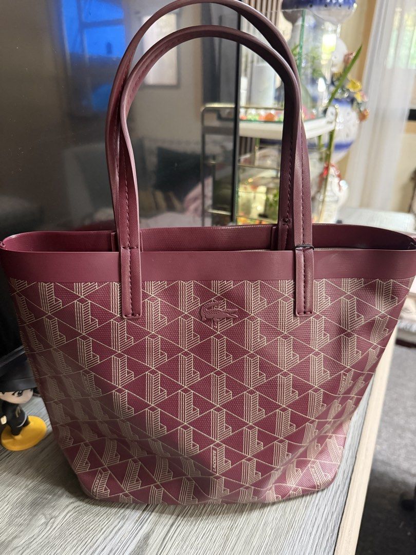 Lacoste Monogram Tote Bag with Matching Pouch (Category: Luxury Bags & Wallets) located in Mariveles. Submitted by ohmyjeys20138 (Listing ID 1454795054, Image 2). Description: 💯 authentic see photos for orig price - Chic maroon tote bag featuring the signature Lacoste monogram pattern. - Includes a matching zippered pouch for extra organization. - Sturdy handles for comfortable carrying. - Spacious interior, ideal for everyday essentials or trav