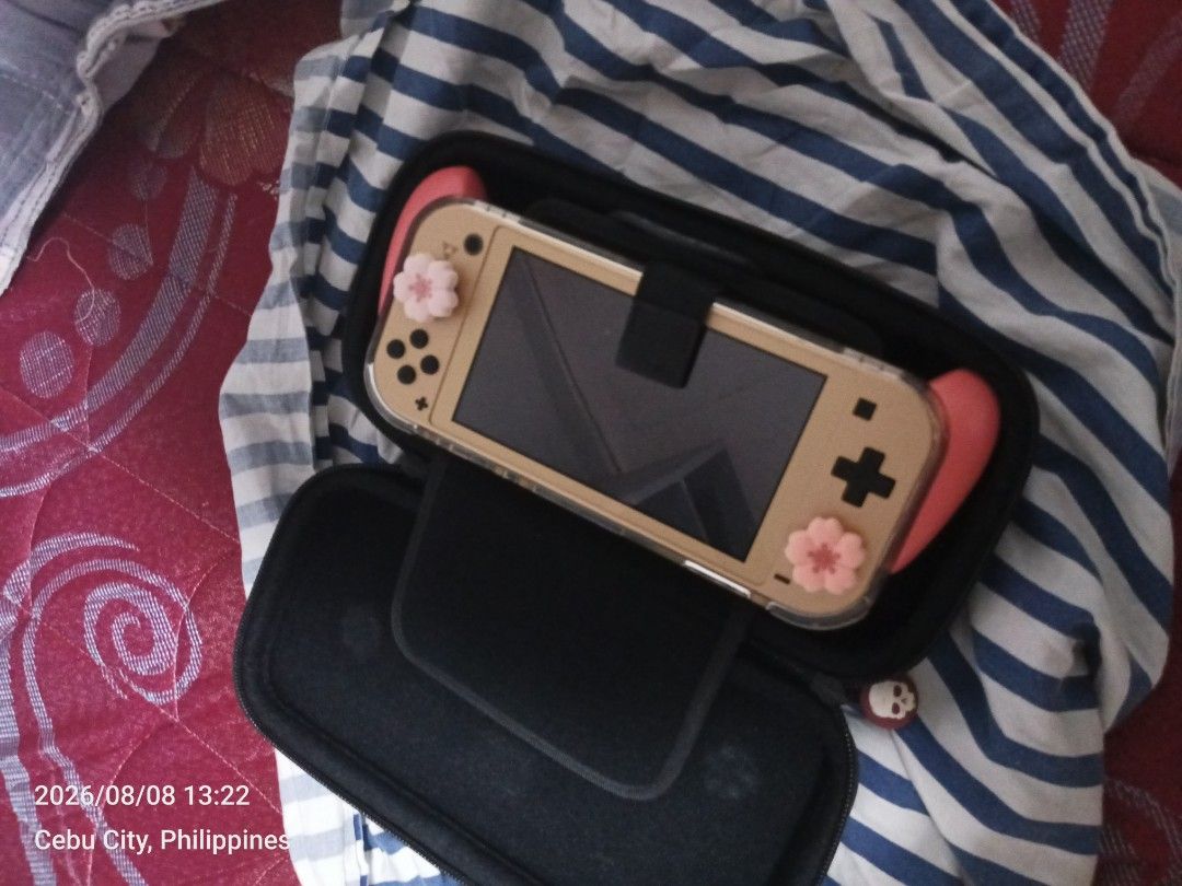 Nintendo Switch Lite Gold with Case and Accessories (Category: Nintendo) located in Cebu City. Submitted by lattyq (Listing ID 1454947395, Image 3). Description: - Gold Nintendo Switch Lite - Includes protective case - Comes with pink grip covers - Features a Zelda-themed backplate - Great for gaming on the go.