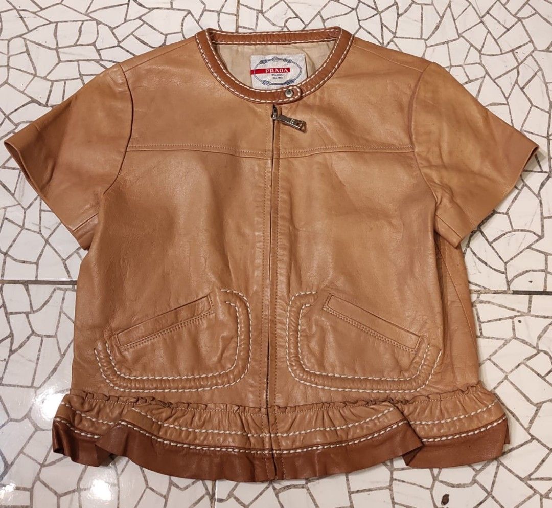 PRADA Brown Leather Short Sleeve Ruffle Jacket (Category: Luxury Apparel) located in Malolos. Submitted by highkeys (Listing ID 1454882097, Image 1). Description: - Prada brown leather jacket - Unique short sleeve design - Elegant ruffle hem - Stylish white contrast stitching throughout - Two functional front pockets - Secure zipper closure -Lenght 18" -width 17".