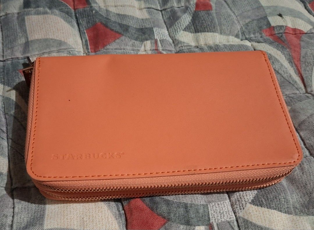 Starbucks Orange Zip Around Wallet (Category: Wallets & Card holders) located in Muntinlupa City. Submitted by abunching (Listing ID 1454867833, Image 1). Description: - Orange Starbucks wallet - Zip-around closure for security - Multiple card slots inside for organization - Rose gold zipper pulls with Starbucks logo - Compact and convenient for everyday use.