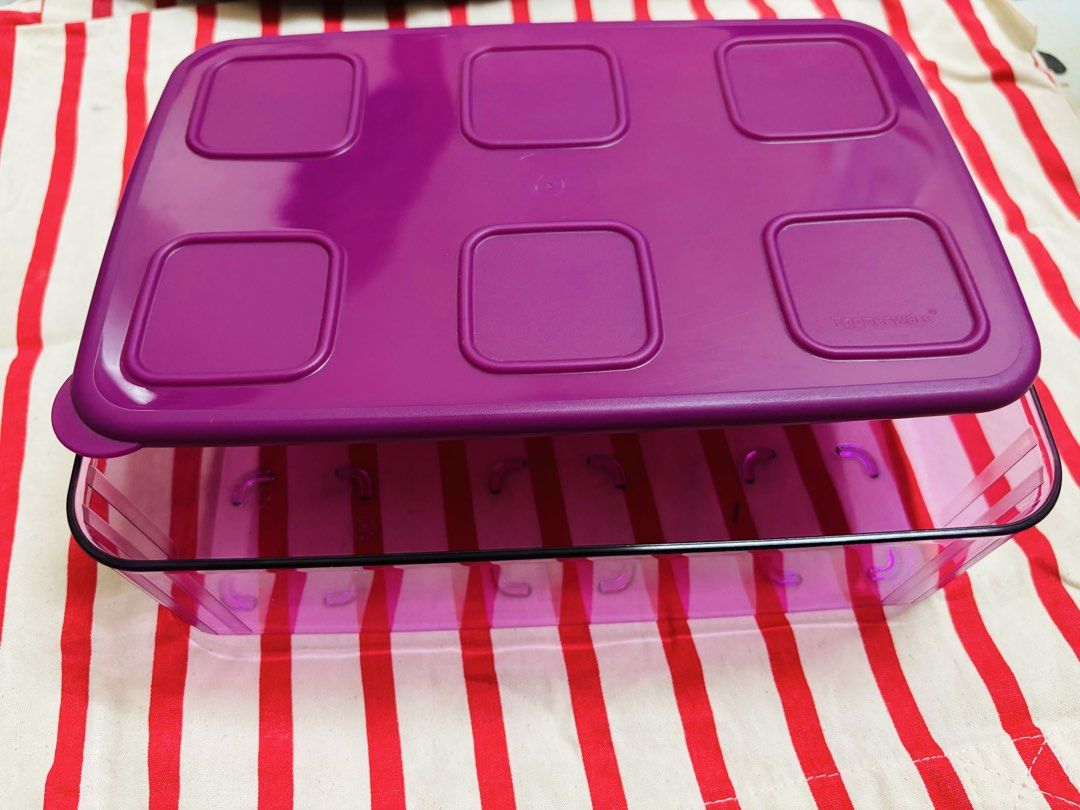 Tupperware Container (Category: Packaged & Instant Food) located in Rawang. Submitted by Mallll (Listing ID 1454819210, Image 2). Description: - Brand: Tupperware - Color: Purple - Design: Features a lid with six square indentations - Condition: Good, pre-loved (10/10) - Material: Tupperware - Use: Ideal for food storage and organization - Original from Tupperware or moneyback guarantee PM FOR SERIOUS BUYER ONLY.