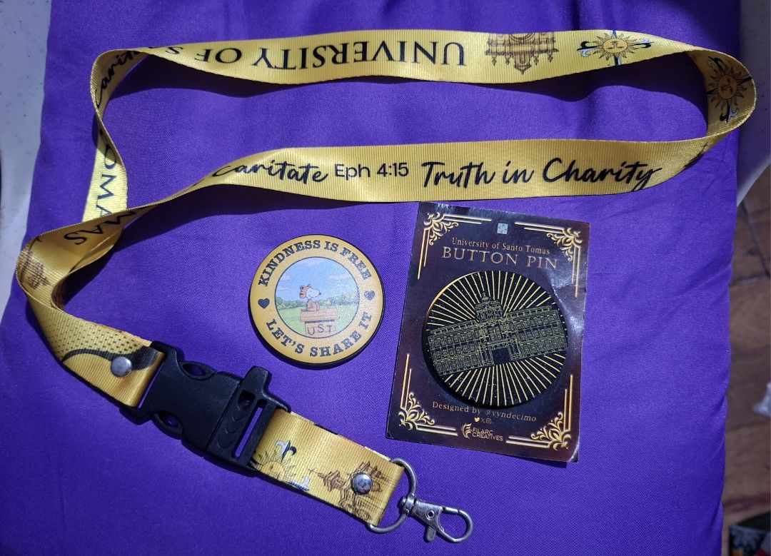 UST Lanyard, Button Pin, and Snoopy Pin (Category: Character Goods) located in Muntinlupa City. Submitted by abunching (Listing ID 1454866977, Image 1). Description: - University of Santo Tomas (UST) lanyard with a secure buckle. - Includes a UST button pin featuring the iconic main building. - Comes with a round Snoopy pin that says 'Kindness is Free, Let's Share It' and 'UST'. - Ideal gift or accessory for any proud Thomasian!.