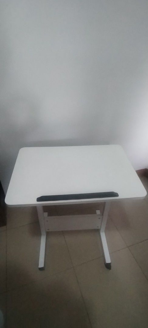 White Adjustable Laptop Desk with Wheels (Category: Tables & Sets) located in Quezon City. Submitted by jebiehn (Listing ID 1454812628, Image 1). Description: - White tabletop with comfortable black wrist rest - Sturdy metal legs with wheels for effortless mobility - Versatile use: bedside table, standing desk, study table - Ideal for work-from-home and online learning - Portable and easy to move around your space.
