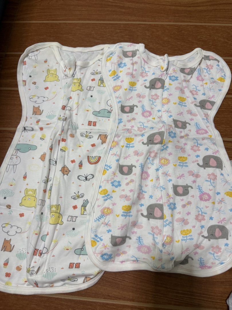 Baby Swaddle Sleep Sacks (Category: Babies & Kids Fashion) located in San Fernando. Submitted by epreloveditems (Listing ID 1455112231, Image 1). Description: - Set of 2 baby swaddle sleep sacks - Design 1: Yellow cat, bunny, clouds, and rainbow print - Design 2: Pink and blue floral pattern with grey elephants - Features easy-to-use zippers for quick dressing - Promotes cozy and secure sleep for your little one.