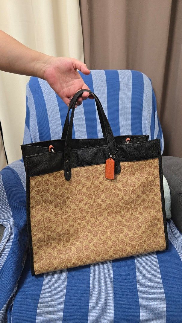 Coach Signature Canvas & Leather Tote Bag (Category: Luxury Bags & Wallets) located in Manila. Submitted by preownedddd (Listing ID 1455082015, Image 1). Description: - Coach tote bag with iconic signature C print - Black leather trim and handles for a classic look - Interior includes a zip pocket and slip pockets for organization - Eye-catching orange accents on the straps - Generously sized main compartment for all your essentials - Ideal for e