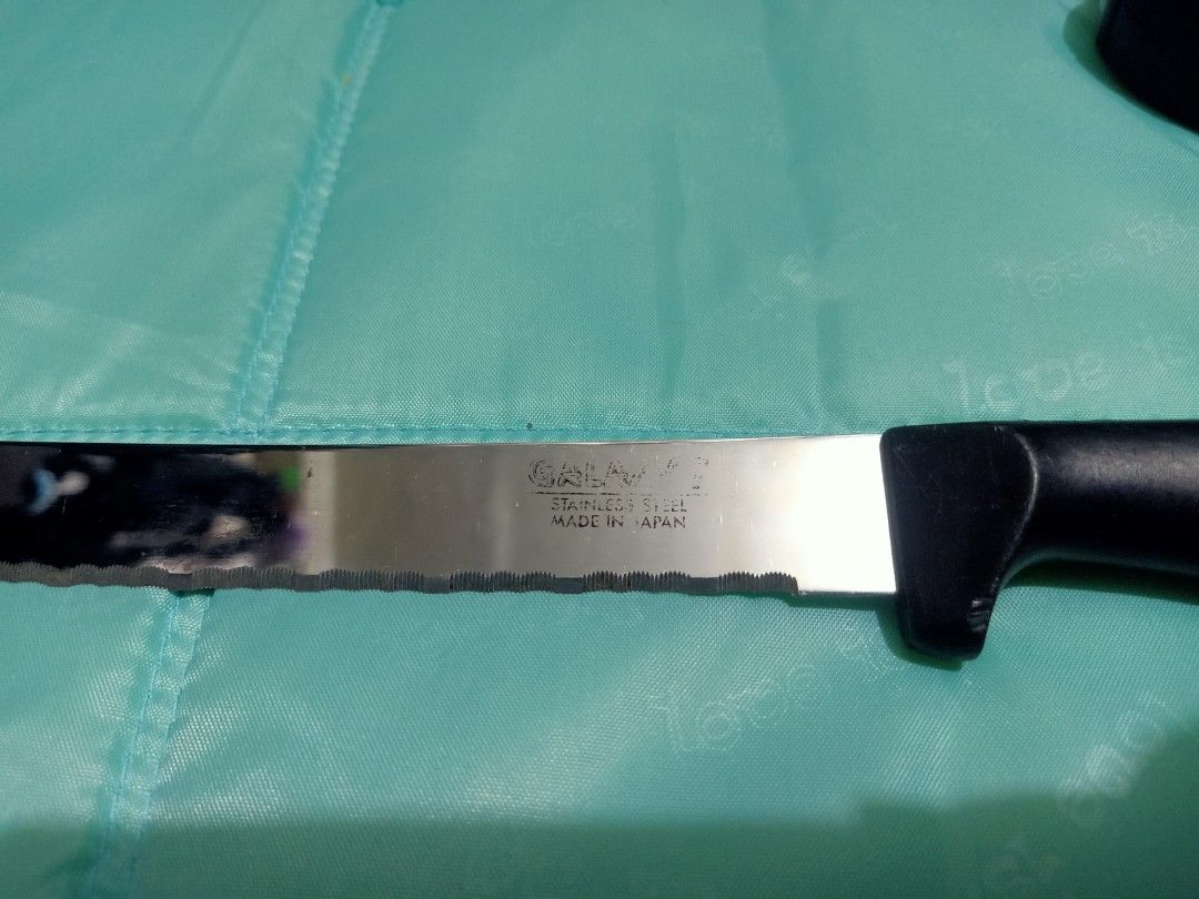 Galaxy stainless steel serrated bread knife (Category: Knives & Chopping Boards) located in Pasig City. Submitted by urdal01 (Listing ID 1455110016, Image 1). Description: - Galaxy stainless steel serrated bread knife with a black plastic handle, featuring a wavy edge and stamped text on the blade indicating it is made of stainless steel. -made in japan -Blade Type: Long, serrated/wavy edge designed for slicing through crusty bread or soft cakes 
