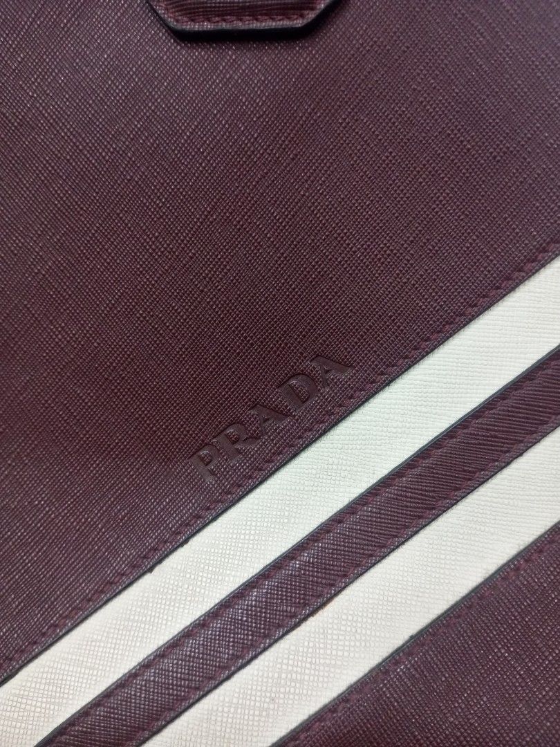 Prada Burgundy Leather Briefcase Bag with White Stripes (Category: Luxury Bags & Wallets) located in Bacolod City. Submitted by exequelgra46775 (Listing ID 1455081365, Image 2). Description: - Authentic Prada burgundy leather Documents Briefcase bag - Features two distinctive white stripes on the front - Secure zipper closure - Interior includes original Prada Made in Italy tag - Durable metal hardware on the zipper - Sturdy and comfortable handl