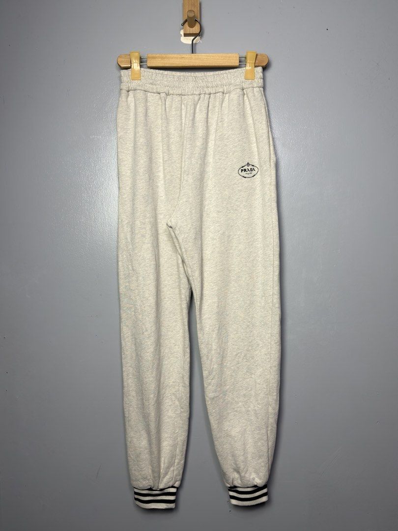 Prada Grey Sweatpants with Striped Cuffs (Category: Joggers) located in Manila. Submitted by dipdrip (Listing ID 1455081610, Image 1). Description: - Prada grey sweatpants - Comfortable and stylish design - Elastic waistband with adjustable drawstring - Ribbed cuffs featuring classic navy and white stripes - Subtle Prada logo detail on the left thigh - Ideal for lounging at home or casual everyday wear DIMENSIONS Waist : 28 can stretch to 34 Leng
