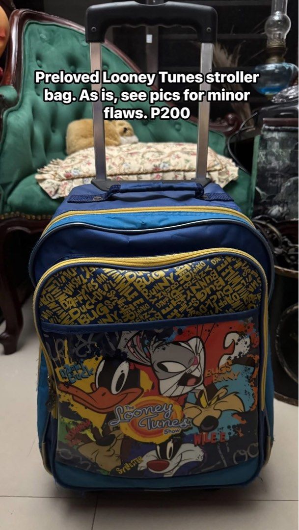 Preloved Looney Tunes Stroller Bag with Wheels (Category: Strollers) located in Cainta. Submitted by elainelawenko (Listing ID 1455035193, Image 1). Description: - Blue stroller bag featuring fun Looney Tunes characters - Equipped with wheels and a retractable handle for easy transport - Spacious interior, perfect for travel or school essentials - Please note: Minor flaws include a small hole and some exposed piping.