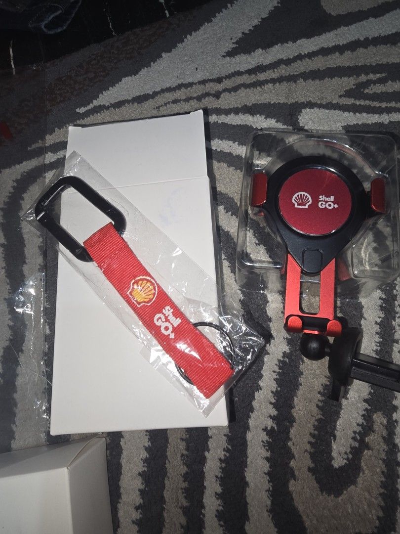 Shell GO+ Car Phone Holder & Keychain Set (Category: Mounts & Holders) located in Quezon City. Submitted by zmmpreloved (Listing ID 1455126252, Image 1). Description: - Genuine Shell GO+ branded phone holder and keychain set. - Phone holder features an adjustable design and clips securely to car air vents. - Keychain includes a sturdy metal carabiner for easy attachment. - Ideal for car enthusiasts or as a thoughtful gift..