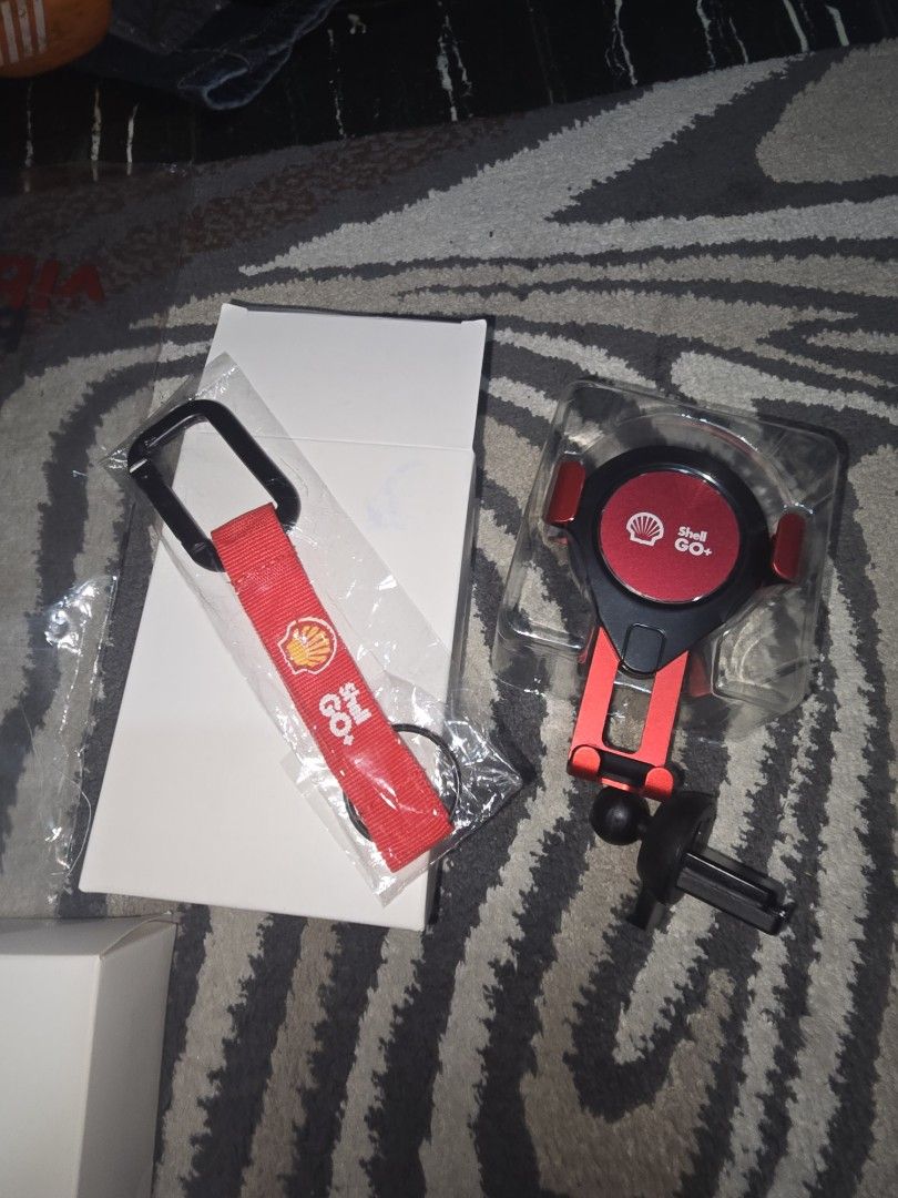Shell GO+ Car Phone Holder & Keychain Set (Category: Mounts & Holders) located in Quezon City. Submitted by zmmpreloved (Listing ID 1455126252, Image 2). Description: - Genuine Shell GO+ branded phone holder and keychain set. - Phone holder features an adjustable design and clips securely to car air vents. - Keychain includes a sturdy metal carabiner for easy attachment. - Ideal for car enthusiasts or as a thoughtful gift..