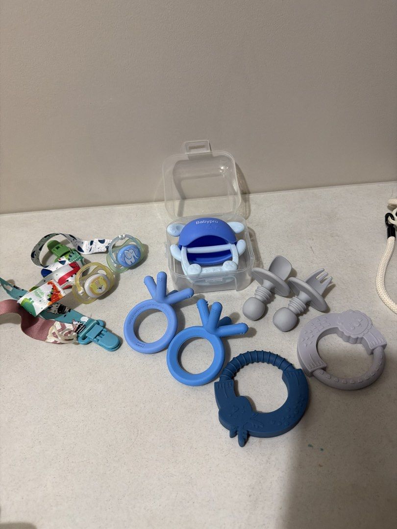 Baby Teethers, Pacifiers, and Pacifier Clips Set (Category: Soothers & Pacifiers) located in Taytay. Submitted by thestyletwins (Listing ID 1455260424, Image 2). Description: - Bundle of baby teething toys and pacifiers - Includes two pacifier clips with cute animal prints - Comes with a blue pacifier holder - Various shapes and colors for baby to chew on - Perfect for soothing sore gums.