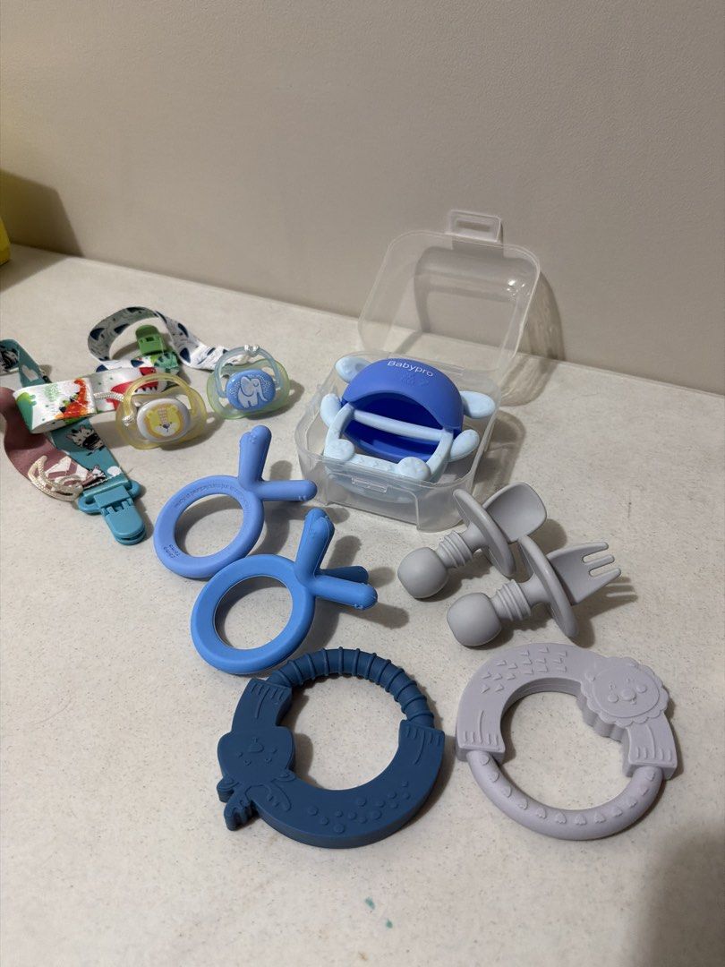 Baby Teethers, Pacifiers, and Pacifier Clips Set (Category: Soothers & Pacifiers) located in Taytay. Submitted by thestyletwins (Listing ID 1455260424, Image 1). Description: - Bundle of baby teething toys and pacifiers - Includes two pacifier clips with cute animal prints - Comes with a blue pacifier holder - Various shapes and colors for baby to chew on - Perfect for soothing sore gums.