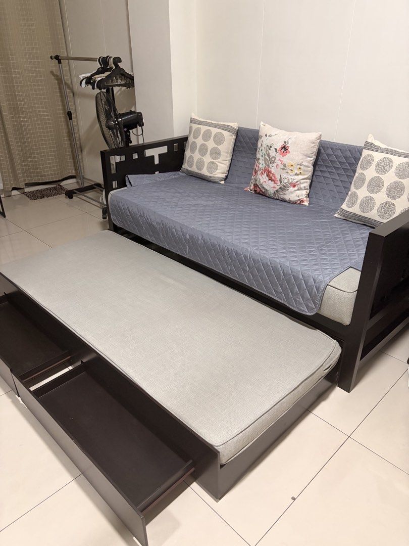 Dark Wood Sofa Bed with Pull-out Trundle and Storage (Category: Sofas) located in Manila. Submitted by miguelfits (Listing ID 1455239505, Image 1). Description: - Dark wood sofa bed with grey quilted fabric - Pull-out trundle for guests - Two built-in storage drawers in trundle frame - Includes 3 decorative pillows - Ideal for small spaces.