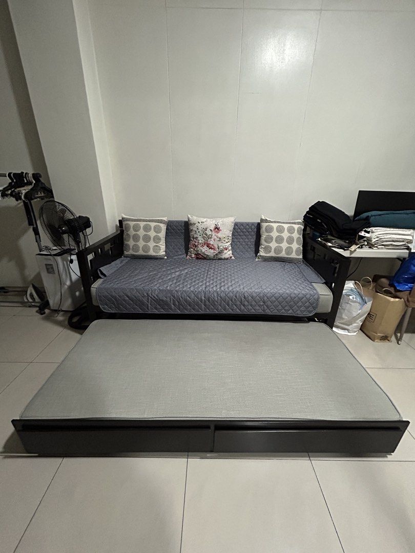 Dark Wood Sofa Bed with Pull-out Mattress and Storage (Category: Sofas) located in San Juan City. Submitted by curatedbymae (Listing ID 1455240926, Image 2). Description: Item: Dark Wood Sofa Bed with Pull-out Mattress and Storage - Versatile Sofa Bed - Dark and solid Wood Frame - Grey Pull-Out Mattress (fabric) - Two Underneath Storage Drawers - Ideal for Small Spaces & Guest Rooms - Easy Sofa-to-Bed Conversion - Quilt cover and 3 decorative pil