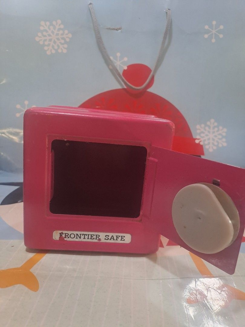 Frontier Safe Pink Combination Lock box Bank (Category: Safe) located in Davao. Submitted by bravemoon_556cd5 (Listing ID 1455296784, Image 3). Description: - Pink metal piggy bank - Features a combination lock for security - Slot for both coins and bills - Easy access storage compartment - Opening instructions located on the bottom - Distributed by Five Below, Inc. - Made in Taiwan - Shows minor scuffs from previous use.