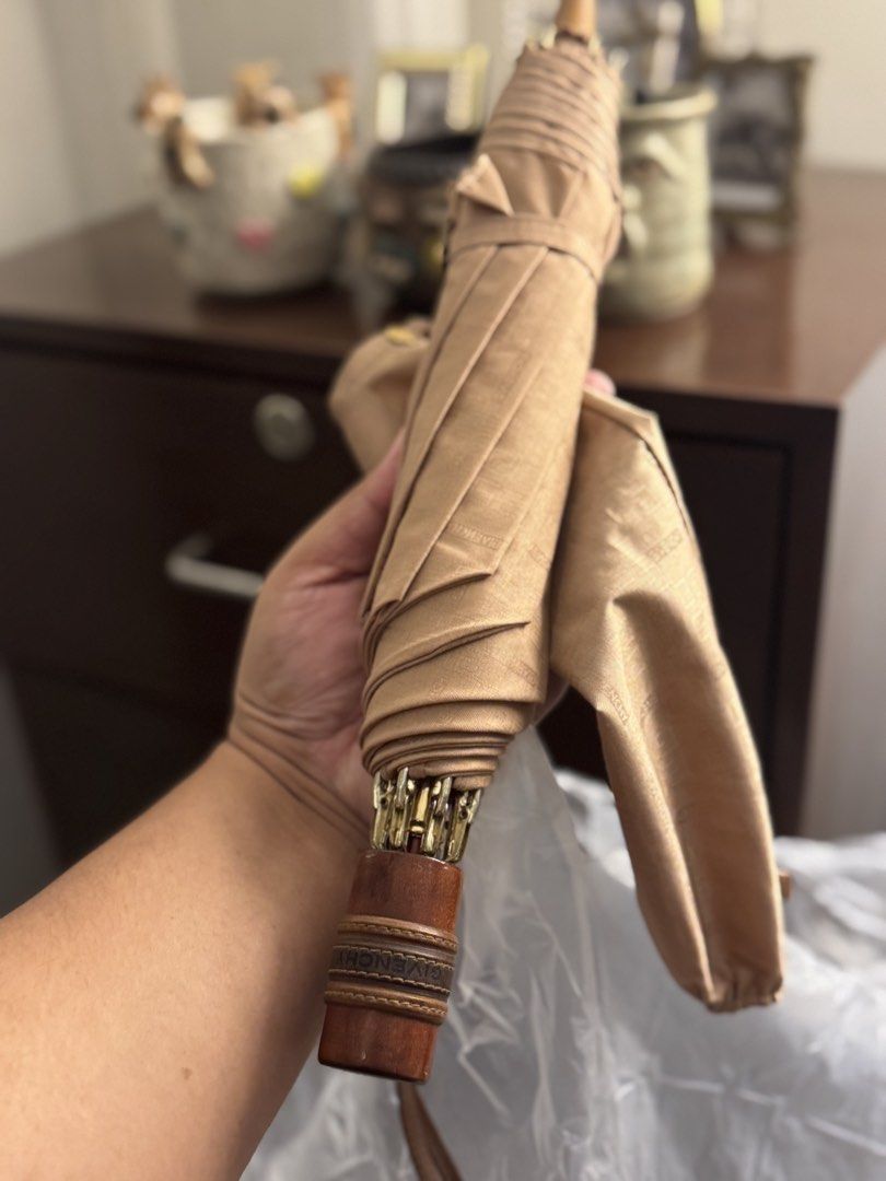 Givenchy Umbrella (Category: Umbrellas) located in Makati City. Submitted by ehloysah (Listing ID 1455310486, Image 1). Description: - Classic Givenchy umbrella - Tan color - Wooden handle with engraved detail - Folds up neatly for storage - Ideal for rainy days.