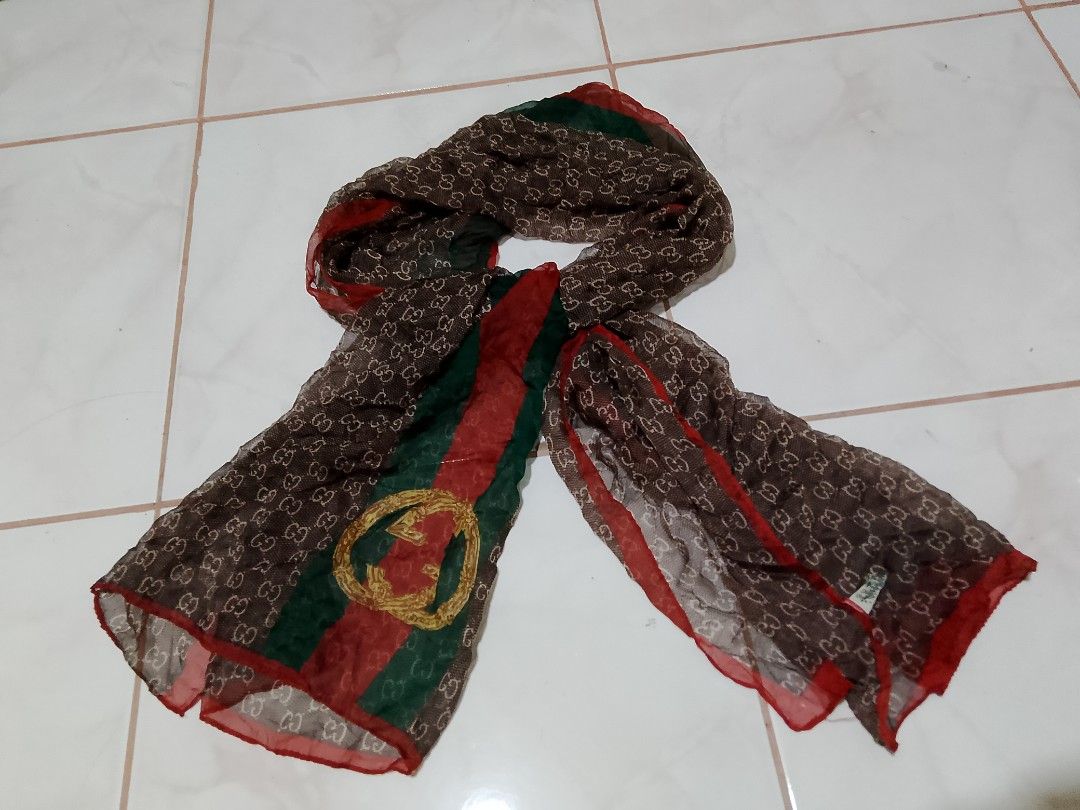 Gucci GG Monogram Scarf (Category: Luxury Accessories) located in Manila. Submitted by magnomicha06972 (Listing ID 1455242238, Image 1). Description: - Authentic Brown Gucci Scarf - Iconic GG Monogram Pattern - Features Red & Green Stripe - Embellished with Gold GG Logo - Lightweight Material - Versatile Accessory to Elevate Any Outfit.