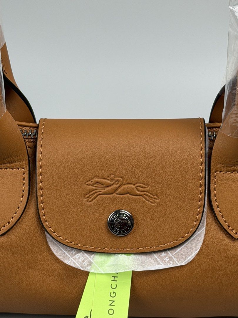 Longchamp Le Pliage S Shoulder Bag (Category: Luxury Bags & Wallets) located in Angeles City. Submitted by gobagsto (Listing ID 1455291005, Image 3). Description: - Authentic Longchamp brown leather shoulder bag - Small size - Signature embossed horse logo on flap - Zipper closure - Interior with Longchamp logo pattern - Includes dust bag and authenticity card - Handles still in original plastic wrap.