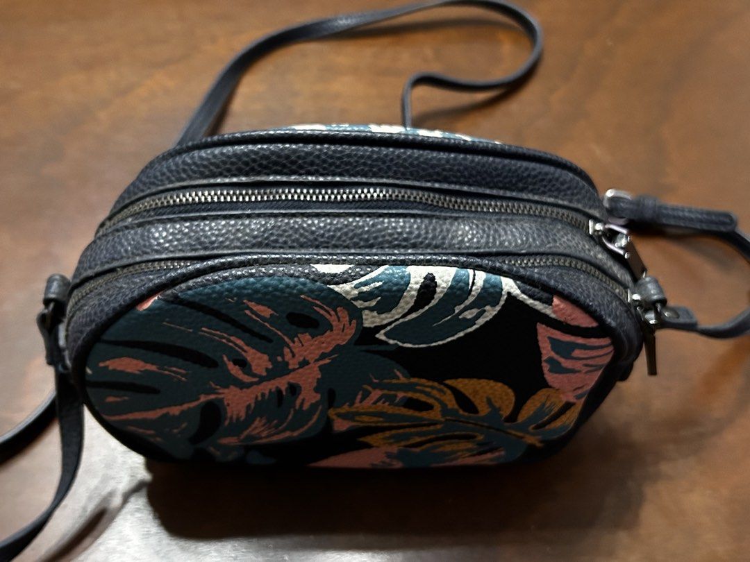 MANGO Oval Crossbody Bag with Tropical Leaf Print (Category: Cross-body Bags) located in Manila. Submitted by my_krophone (Listing ID 1455205243, Image 3). Description: - Cute oval crossbody bag - Fun tropical leaf print (pink, teal, yellow on black background) - Dark navy strap and trim - Two zippered compartments - Ideal for casual outings or travel.