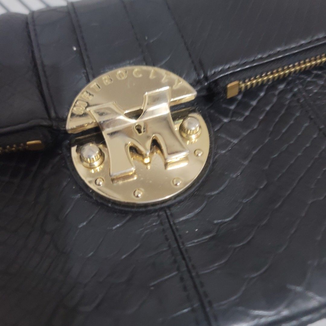 METROCITY Black Leather Embossed Chain Strap Clutch Bag (Category: Luxury Bags & Wallets) located in Pasig City. Submitted by bunny.bella (Listing ID 1455310152, Image 2). Description: Chic black leather Metrocity with gold logo. Zip closure, detachable chain strap. Perfect for essentials. Very good condition Genuine leather.